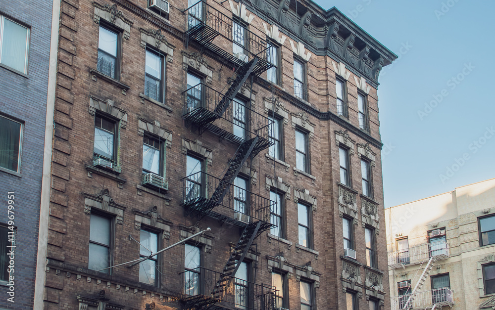 Fototapeta premium Típica fachada de un edificio residencial antiguo de Manhattan en New York, USA. Ventanas y escaleras de incendio en un edificio de la calle Grand.