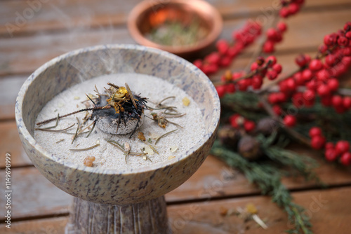 Close-up of a censer with glowing charcoal and aromatic incense (frankincense, copal, spruce needles) on a wooden table. Shot outdoors on a cold winter morning. photo