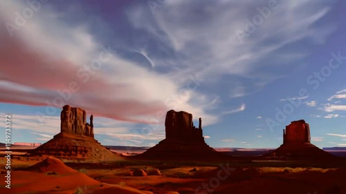 Scenic view of red rock formations under a dramatic sky with clouds.