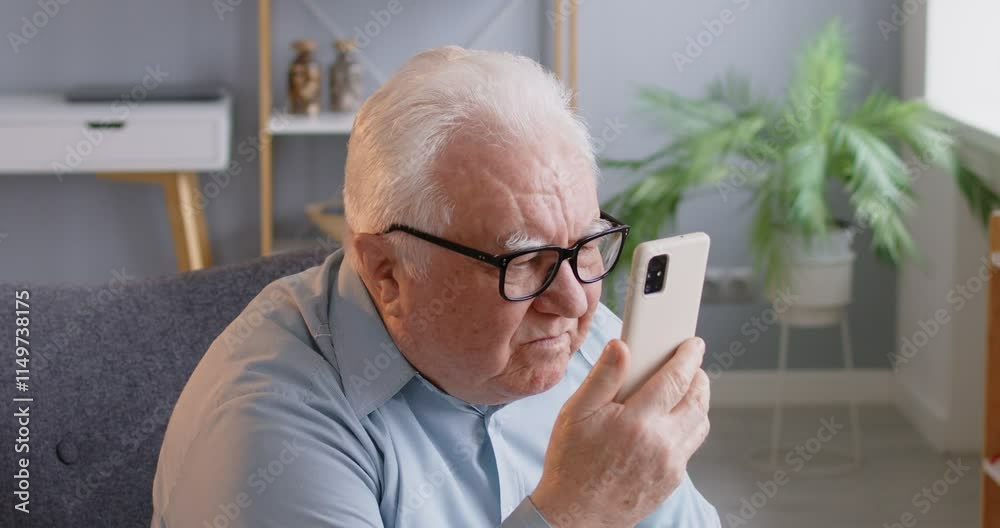 Senior man with poor eyesight is struggling to use the phone at home. Elderly individuals with disabilities and problems, highlighting the importance of accessibility and support for pensioners.