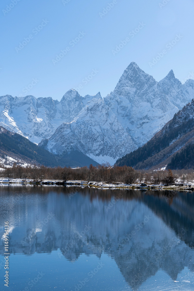 Obraz premium Dombay, Karachay-Cherkessia. Teberda National Park. Lake Tumanly-Gel or Tumanly-Kol (Misty Lake) is in valley of Gonachkhir River. Snowy peaks of Mount Chotcha are reflected in lake as in mirror.