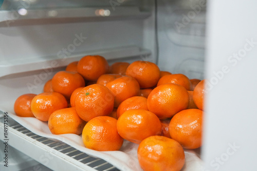 Tangerines or Mandarin oranges displayed in a refrigerator are suitable for use in poster designs, or as illustrations for articles about fruits.