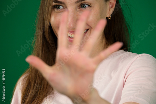 woman expressing herself. different emotions of a young girl on a green background chromakey beautiful facial features real people pink T-shirt white skinned. European photo