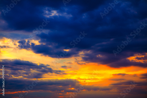 Dramatic sunset sky with vibrant orange and yellow tones blending into deep blue clouds, creating a striking contrast. Perfect for nature and atmospheric themes photo