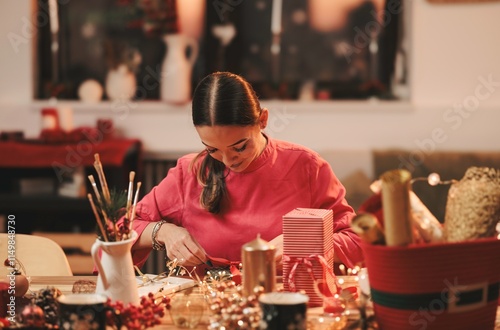 Engaging in a delightful Christmas crafting session, a woman focuses on creating beautiful decorations amidst a backdrop of holiday cheer. Festive supplies surround her, inspiring creativity photo