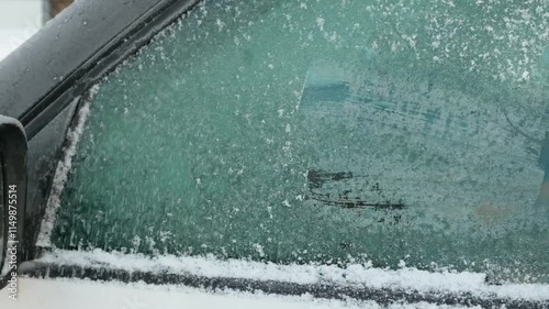 A person cleaning the side windows of a car from snow with ice scraper. Woman removes ice from car windows. Female hand cleans car with special tool in snowy winter day. Slow motion 120fps.