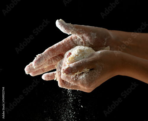 hands knead dough on a black background. photo