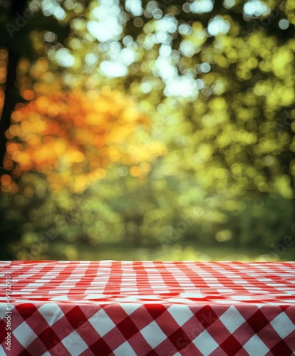 Red checkered tablecloth on picnic table with blurred autumn park background.