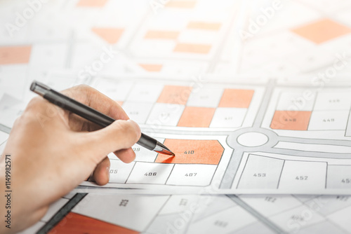 Woman holding a pencil pointing to cadastral map to decide to buy land. real estate concept with vacant land for building construction and housing subdivision for sale, rent, buy, investment.