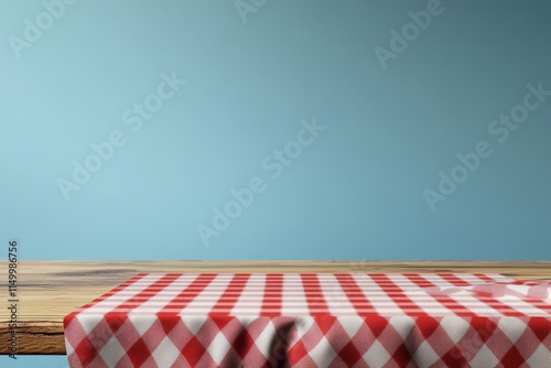 Empty wooden table with red checkered tablecloth against a light blue wall.