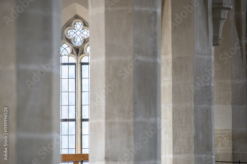 Gotisches Kirchenfenster mit Rosette, Maßwerk und  Bleiverglasung hinter unscharfen achteckigen Steinsäulen in der Stiftskirche in Dettingen an der Erms photo