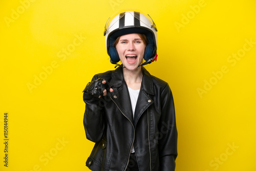 Young English woman with a motorcycle helmet isolated on yellow background surprised and pointing front