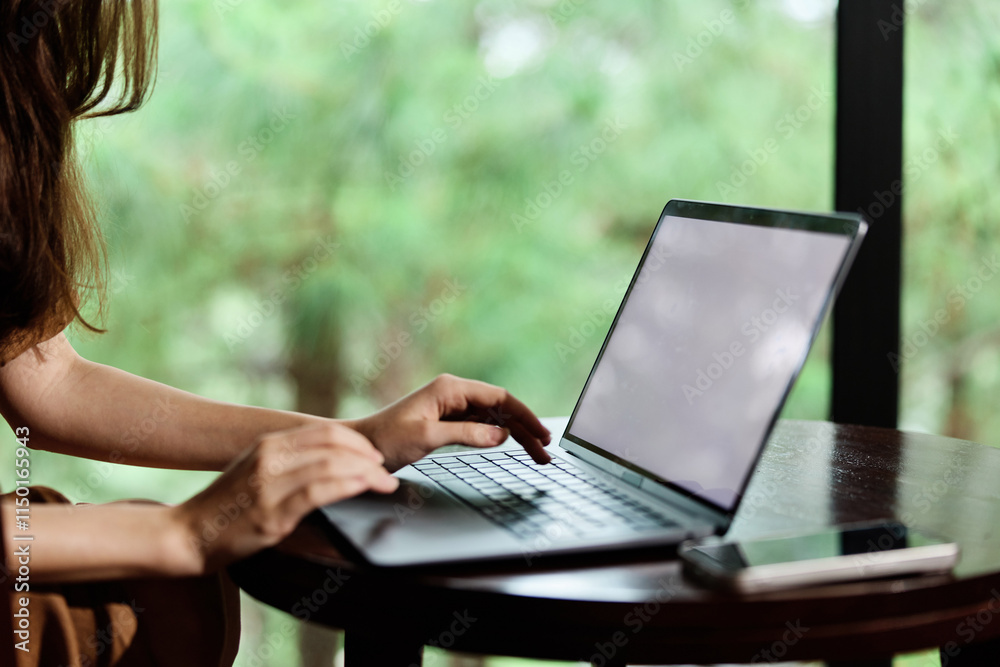 A woman typing on a laptop in a cozy workspace with a green forest background, showcasing concentration and productivity Calm and natural atmosphere A woman typing on a laptop in a cozy workspace with a green forest background, showcasing concentration and productivity Calm and natural atmosphere