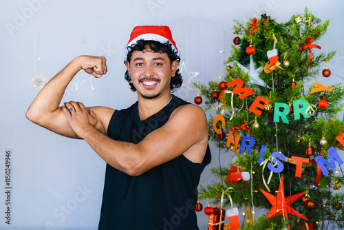 Young Fit Asian Male with dumb bell weights infront of Christmas Tree New Year Fitness Concept Gym photo