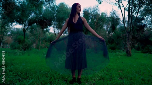 Chica en medio del bosque al anochecer realizando movimientos elegantes e interesantes de fantasía.
