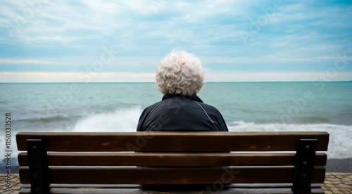 Elderly woman sitting on a bench by the sea, rear view