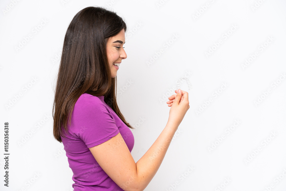 Young Brazilian woman holding invisible braces isolated on white background with happy expression