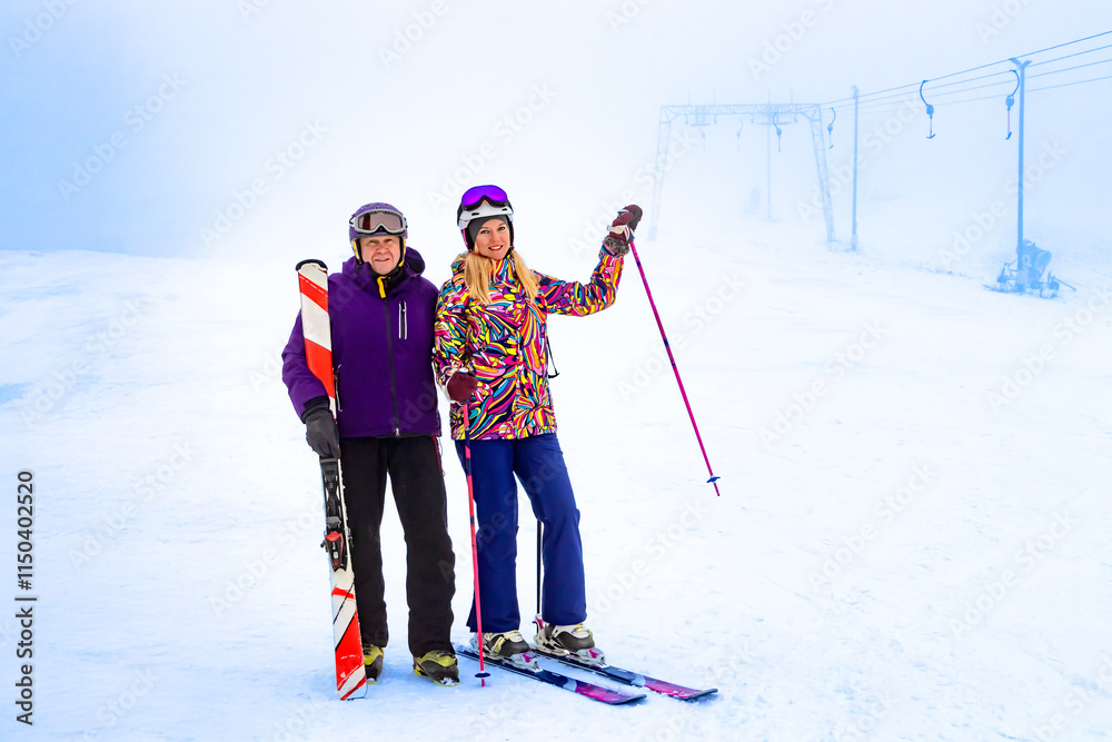 Two father and daughter skiers enjoying a beautiful day on the slopes surrounded by nature and snow