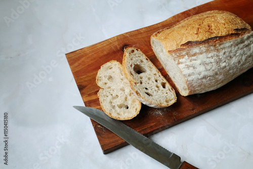 fresh sliced ​​bread on cutting board with knife on marble background top view