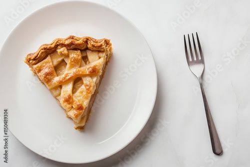 Freshly baked apple pie slice served on a white plate with a fork beside it
