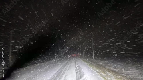 Driving through a snow storm at night on a rural road 