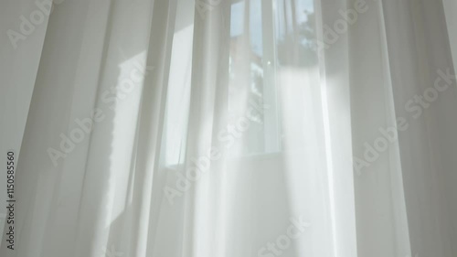 Transparent blurred white silk soft fabrics floating with sunlight shining through, shadows reflected on the textile surface, close up.