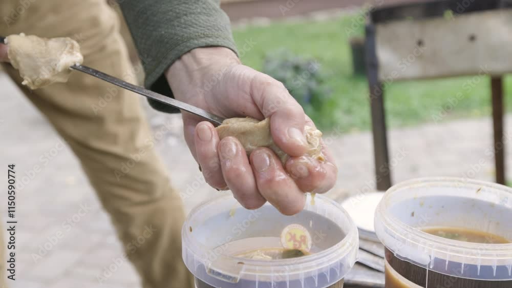 A man putting marinaded shashlik meat on a skewer for barbecue on a warm Summer day. Nr.2