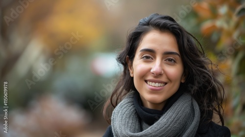 A happy Middle Eastern woman with a radiant smile embraces winter, showcasing warmth amidst nature's beauty