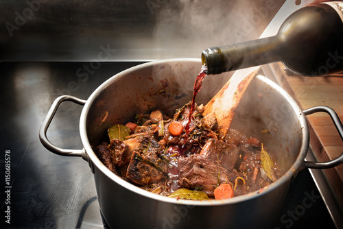 Obraz na plátně Red wine is poured into a stainless steel pot to deglaze the roasted ingredients