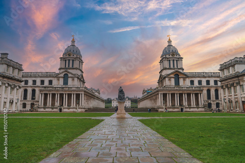 Tableau sur toile The iconic twin domes of the Old Royal Naval College are illuminated by a vibrant sunset, casting a warm glow over the historic architecture and green lawn