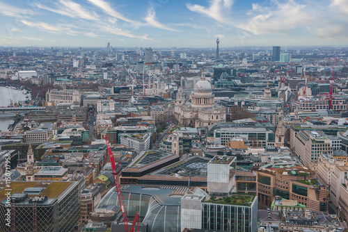 A panoramic view of London with St. Paul's Cathedral at the center, the Thames River on the left, and the BT Tower in the distance under a cloudy sky. photo