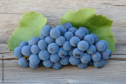 Green grapes arranged on a wooden surface with leaves in a lush garden settin...