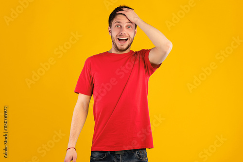 Omg, Wow. Portrait of young shocked handsome guy with open mouth holding hand on his head, looking at camera in amazement and with surprised facial expression, standing isolated over blue background