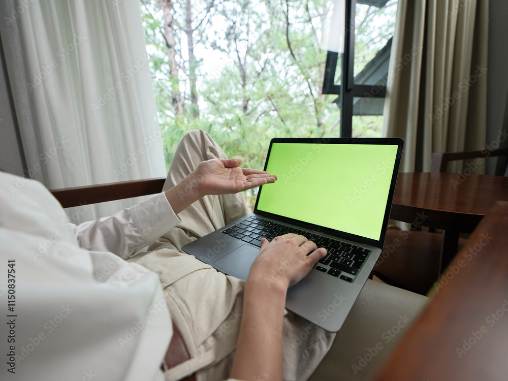Fototapeta premium Young adult working on laptop in minimalistic indoor space with natural light, showcasing modern lifestyle and remote work concept