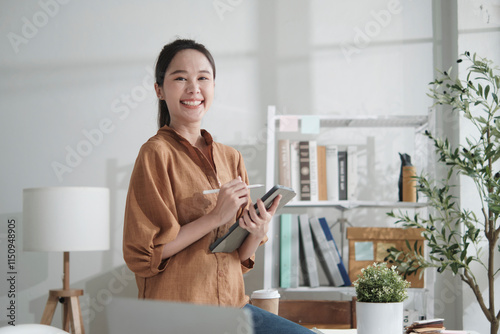 Portrait of beautiful Asian businesswoman, startup entrepreneur smiles and looks at camera in casual small business office, creative marketing E-commerce jobs, happy and cheerful attractive person.