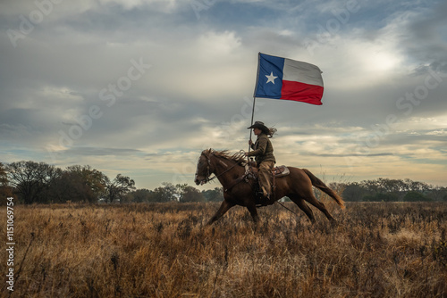 Woman Wearing Cowboy Hat Riding Running Horse While Holding Large Texas Flag In Grassy Field With Cloudy Sky