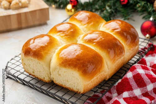 A freshly baked loaf of soft, golden dinner rolls on a cooling rack, surrounded by festive decorations, perfect for holiday gatherings. photo