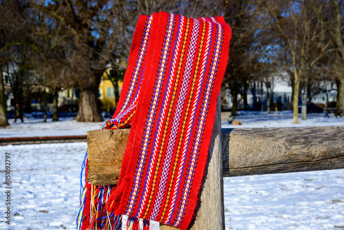 ceinture fléchée (traditional pattern) replica of the woven sash worn by voyageurs during the fur trade shot outside on a wooden fence in the sun with snow room for text
