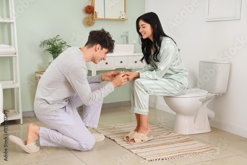 Happy young couple with pregnancy test in bathroom photo