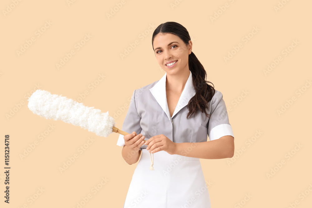 Young chambermaid with pp-duster on beige background Young chambermaid with pp-duster on beige background