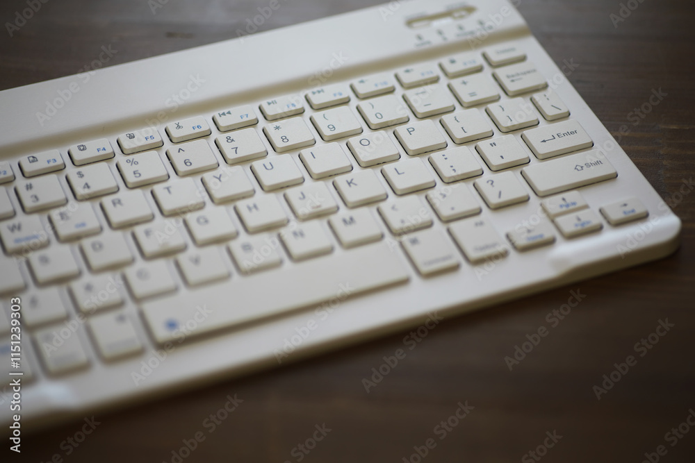 White Wireless Keyboard on Brown Wooden Desk - Minimalist Tech Workspace Stock Photo White Wireless Keyboard on Brown Wooden Desk - Minimalist Tech Workspace Stock Photo