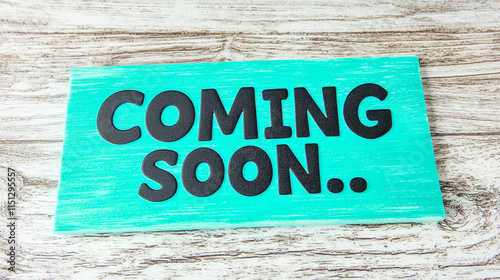 Colorful wooden sign with bold black 'coming soon' text on teal background photo