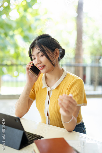 Young asian student talks on mobile while studying at canteen. photo