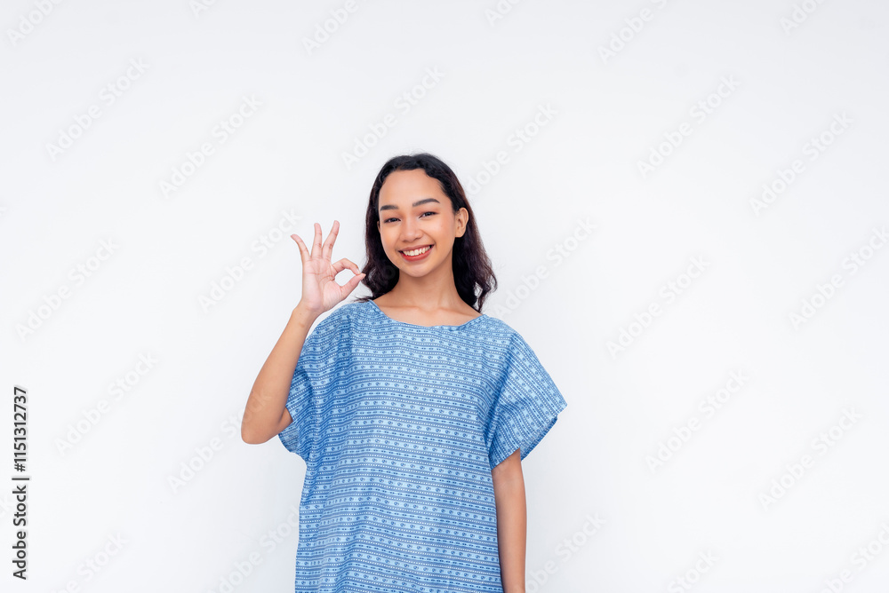 Smiling hospital patient in a blue gown gesturing a positive okay sign