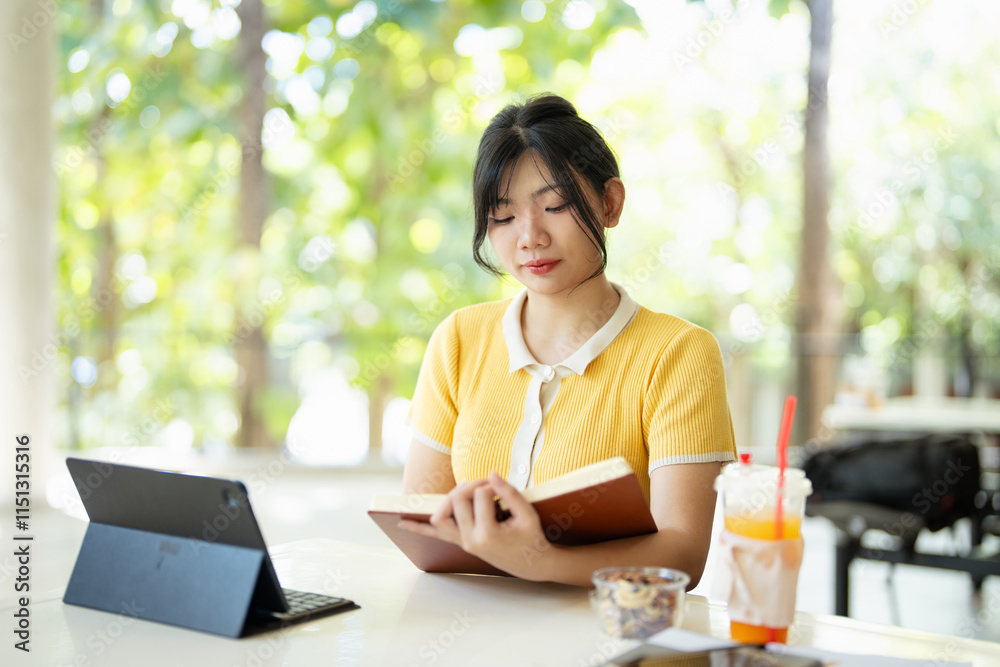 Serious intelligent millennial girl studying in cafe or student canteen preparing for exam test or coursework, doing home assignment, reading notes in exercise book, knowledge and education concept. Serious intelligent millennial girl studying in cafe or student canteen preparing for exam test or coursework, doing home assignment, reading notes in exercise book, knowledge and education concept.