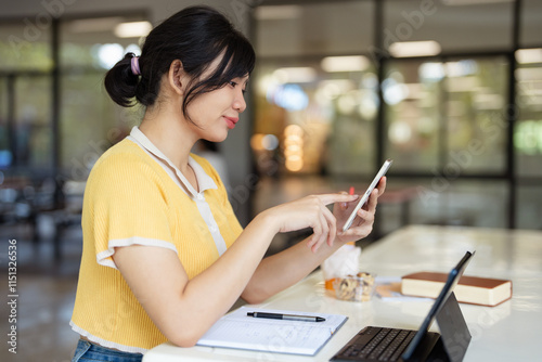 Young teen girl college student holding smartphone studying on cell, distance learning using apps for education, elearning on mobile phone in university campus or creative office. photo