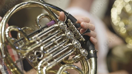 A musician playing their lacquered French horn during a wind band rehearsal before a live performance. Nr.1
