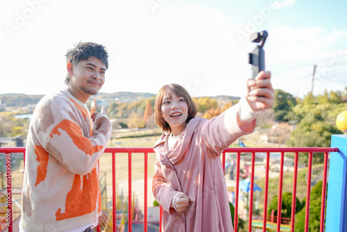 At a large park in Handa City, Aichi Prefecture, a couple in their 20s are having fun playing on the playground equipment and taking selfies with a small camera. photo