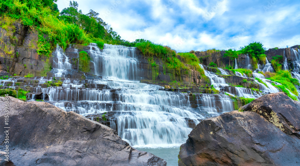 Naklejka premium Mystical waterfall with foreground is autumn leaves in the Da Lat plateau, Vietnam. This is known as the first Southeast Asian waterfall in the wild attracted many tourists to visit