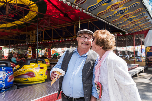 Wallpaper Mural Senior woman kissing man near bumper car at amusement park Torontodigital.ca
